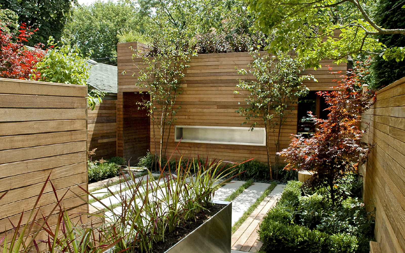 The green roof is a visual extension of the rear garden. Courtyard with planters and view onto a vegetated roof